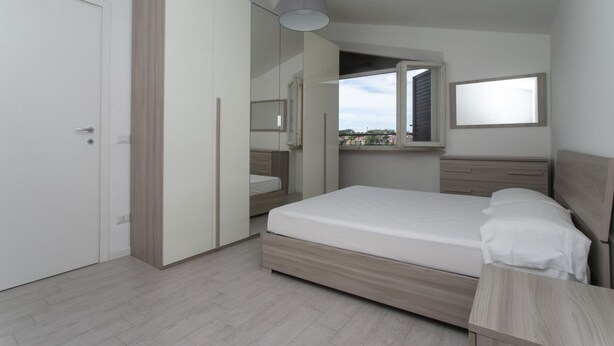 Een slaapkamer met een bed, een kledingkast, een spiegel en een raam.