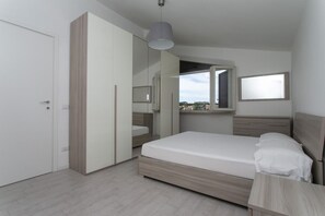 A bedroom with a bed, a wardrobe, a mirror, and a window. - M157 - Marcelli, brand new three-room apartment 250mt from the sea (Marcelli)