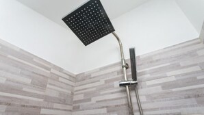Een douche met een vierkante douchekop en een handdouche.