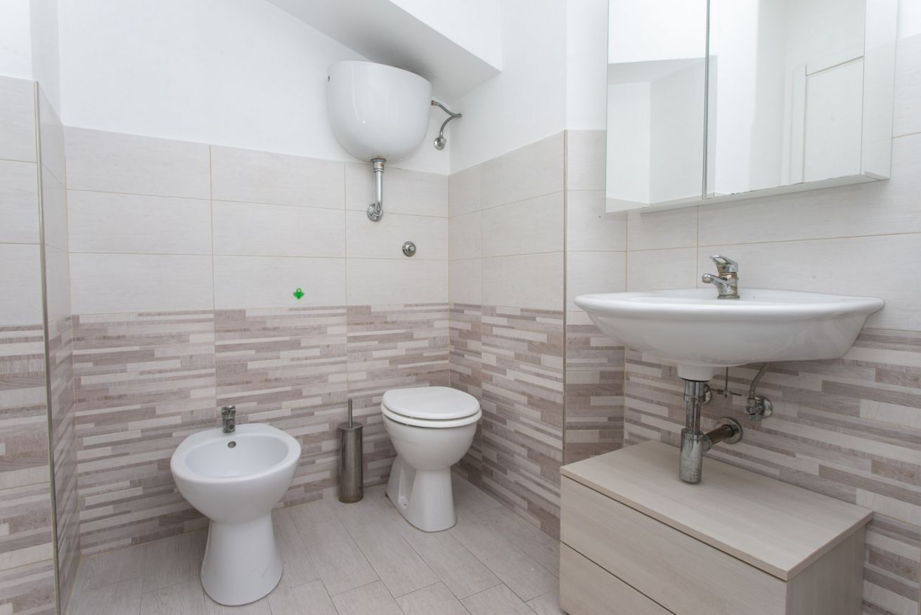 A bathroom with a bidet, toilet, sink, and a mirror above the sink.