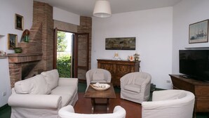 Ein Wohnzimmer mit Kamin aus Backstein, einem Fernseher und einem Esstisch.