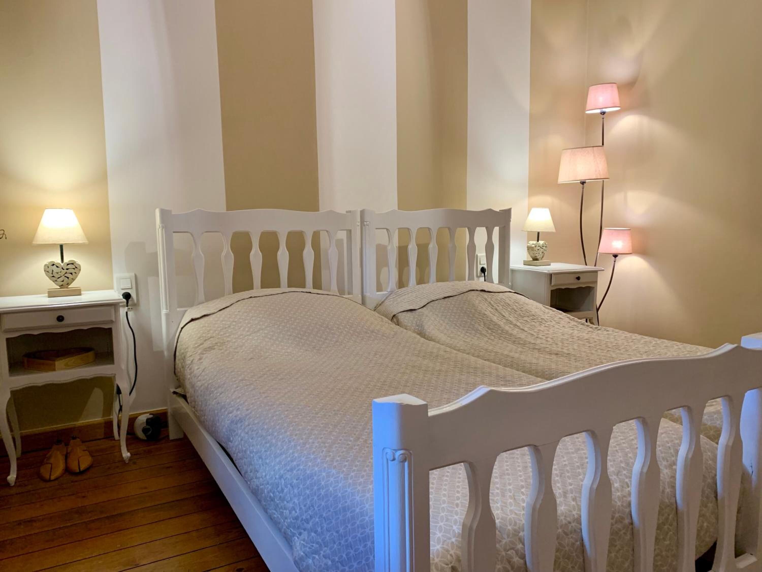 Ein Schlafzimmer mit einem weißen Bett, zwei Nachttischen mit Lampen und einem Holzboden.