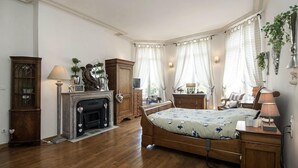 Een slaapkamer met een houten bed, een open haard, een bureau met een lamp en een kledingkast.