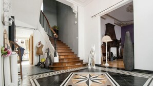 Een statige trap met een modern ontwerp, die leidt naar een kamer met een grote vaas en een lamp.