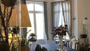 Een eethoek met een lange tafel, stoelen en een bloevas.