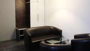 A modern room with a dark brown leather sofa, a glass coffee table, and a white wardrobe. - Apartment Caplex (Oldenburg)
