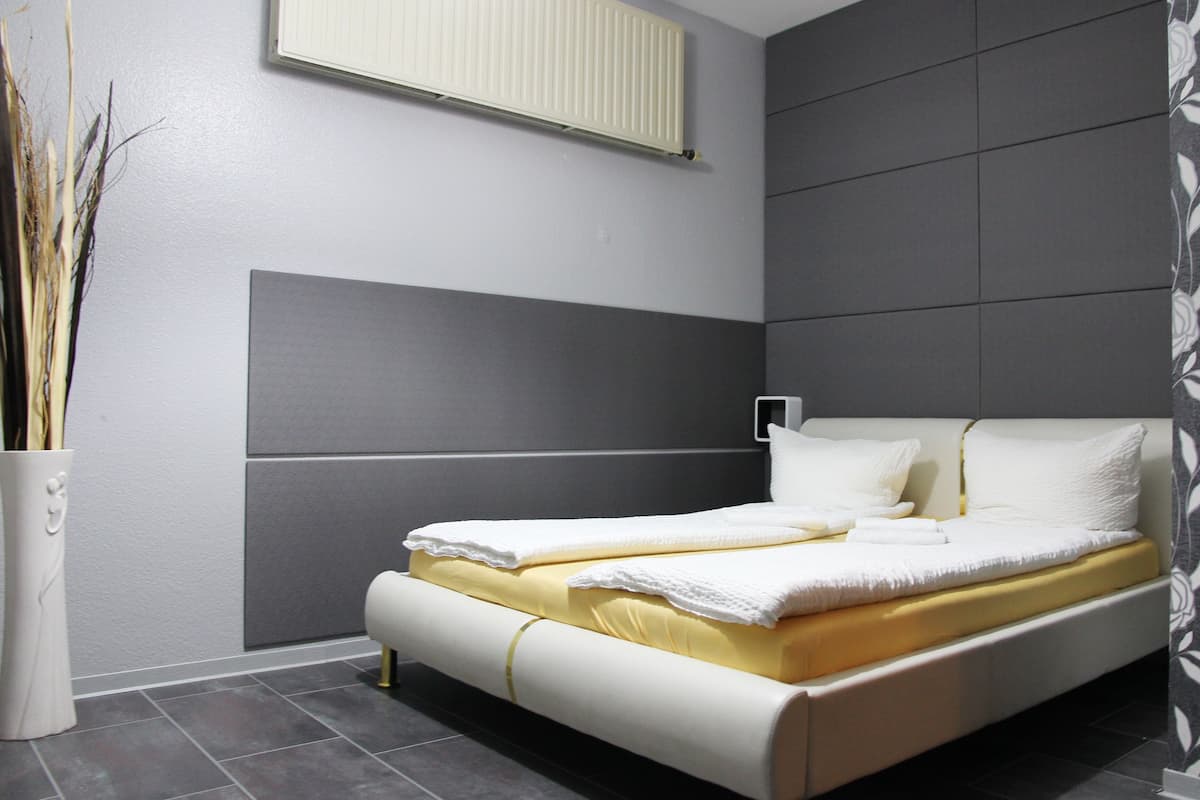 Un dormitorio moderno con cama, un radiador y un florero decorativo.