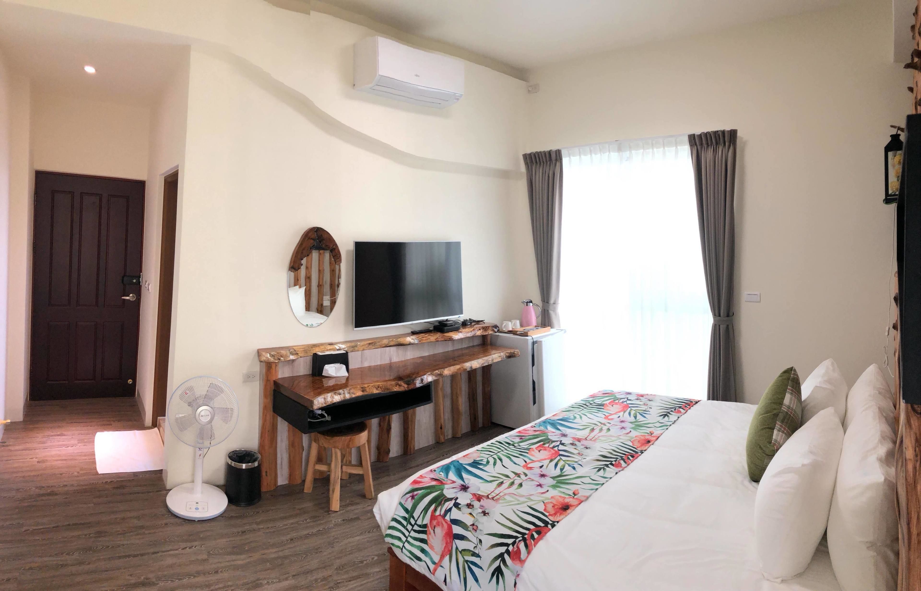 Una habitación de hotel con una cama, un escritorio, un televisor y un equipo de aire acondicionado.