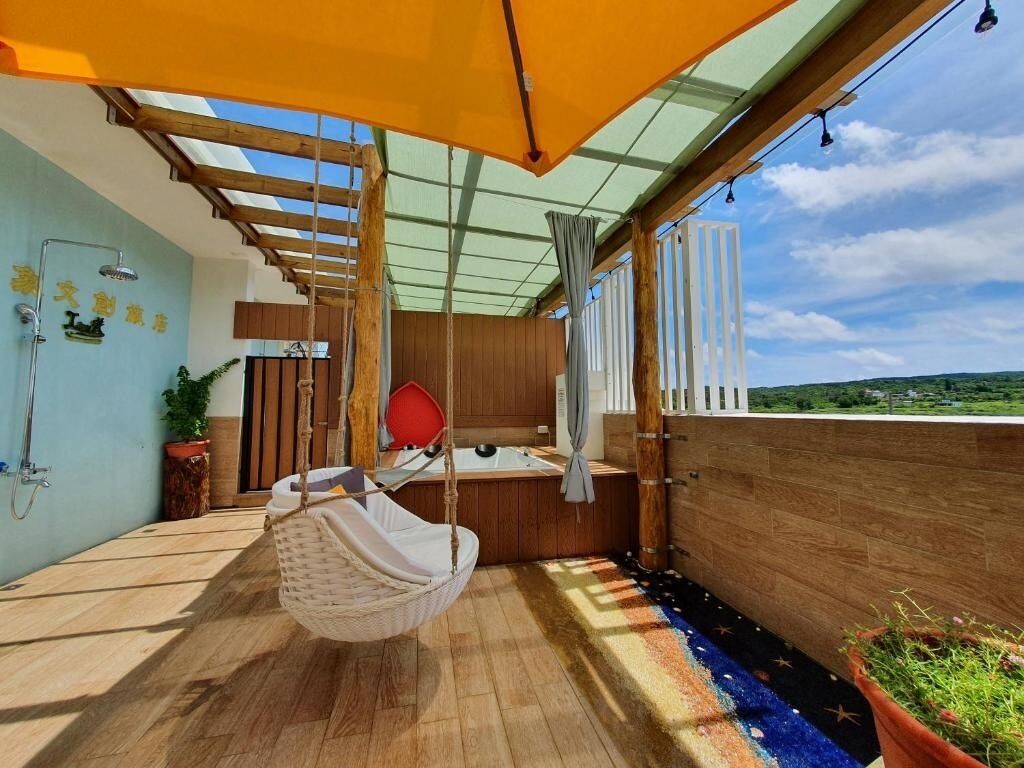 A balcony with a hanging chair, a small sink, and a shower.