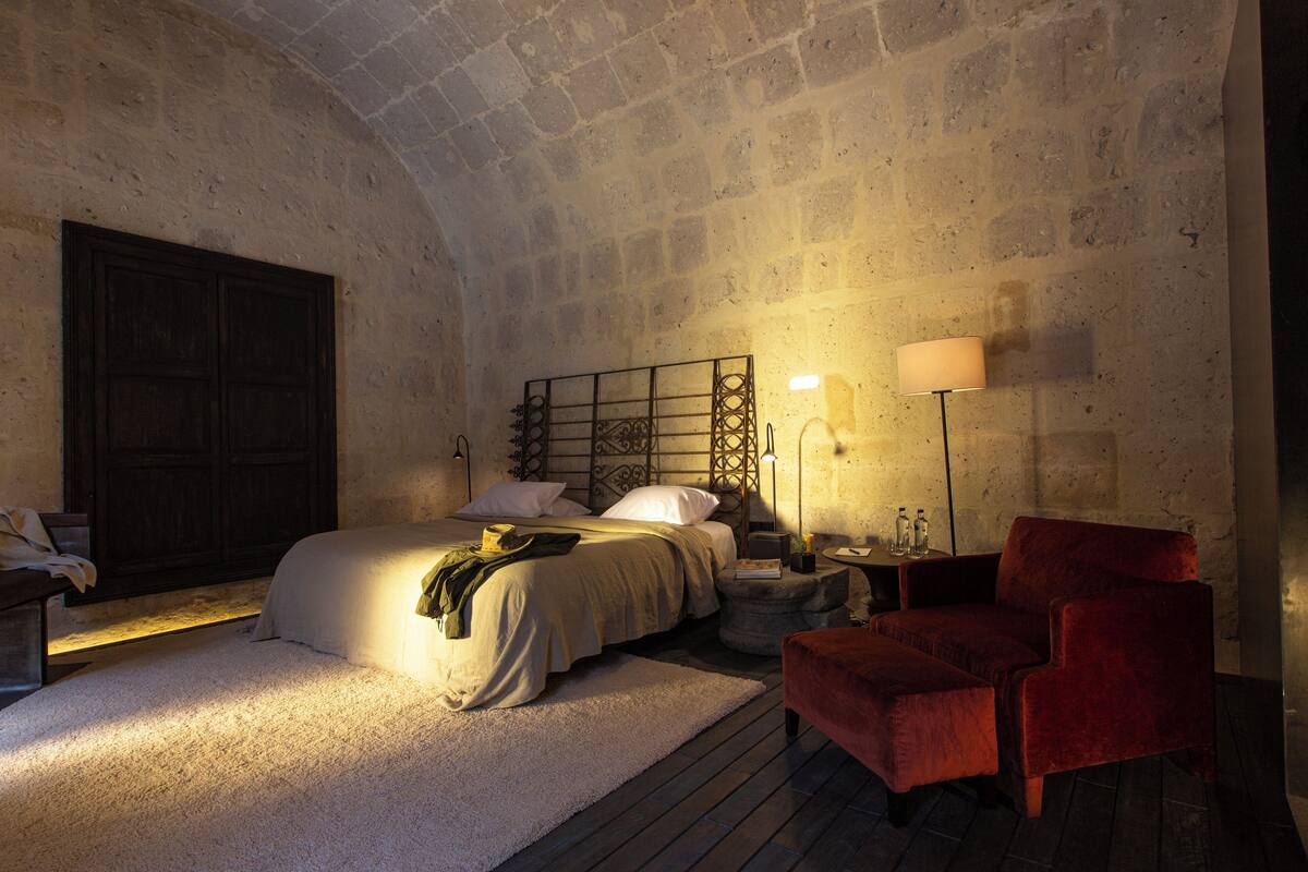 Ein Schlafzimmer mit einem großen Bett, einem roten Sessel, einem Nachttisch und einer Lampe.