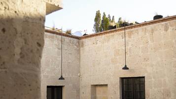A courtyard with a pool, stone walls, and hanging lights.