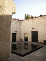 A courtyard with a pool, stone walls, and hanging lights.