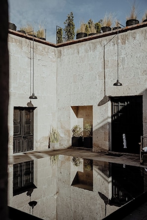 A courtyard with a reflective pool, a door, and potted plants. - CIRQA by Andean (Arequipa)