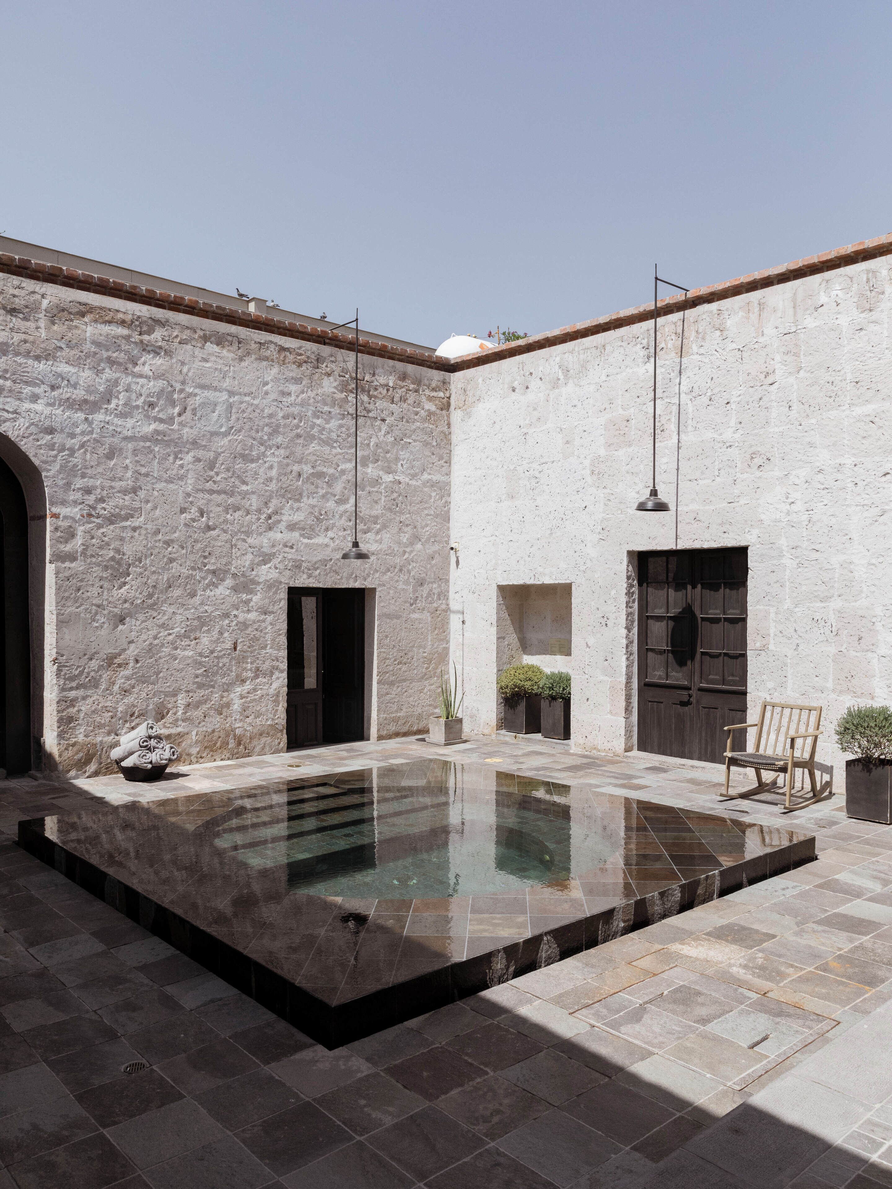 A courtyard with a pool, stone walls, and a wooden door.