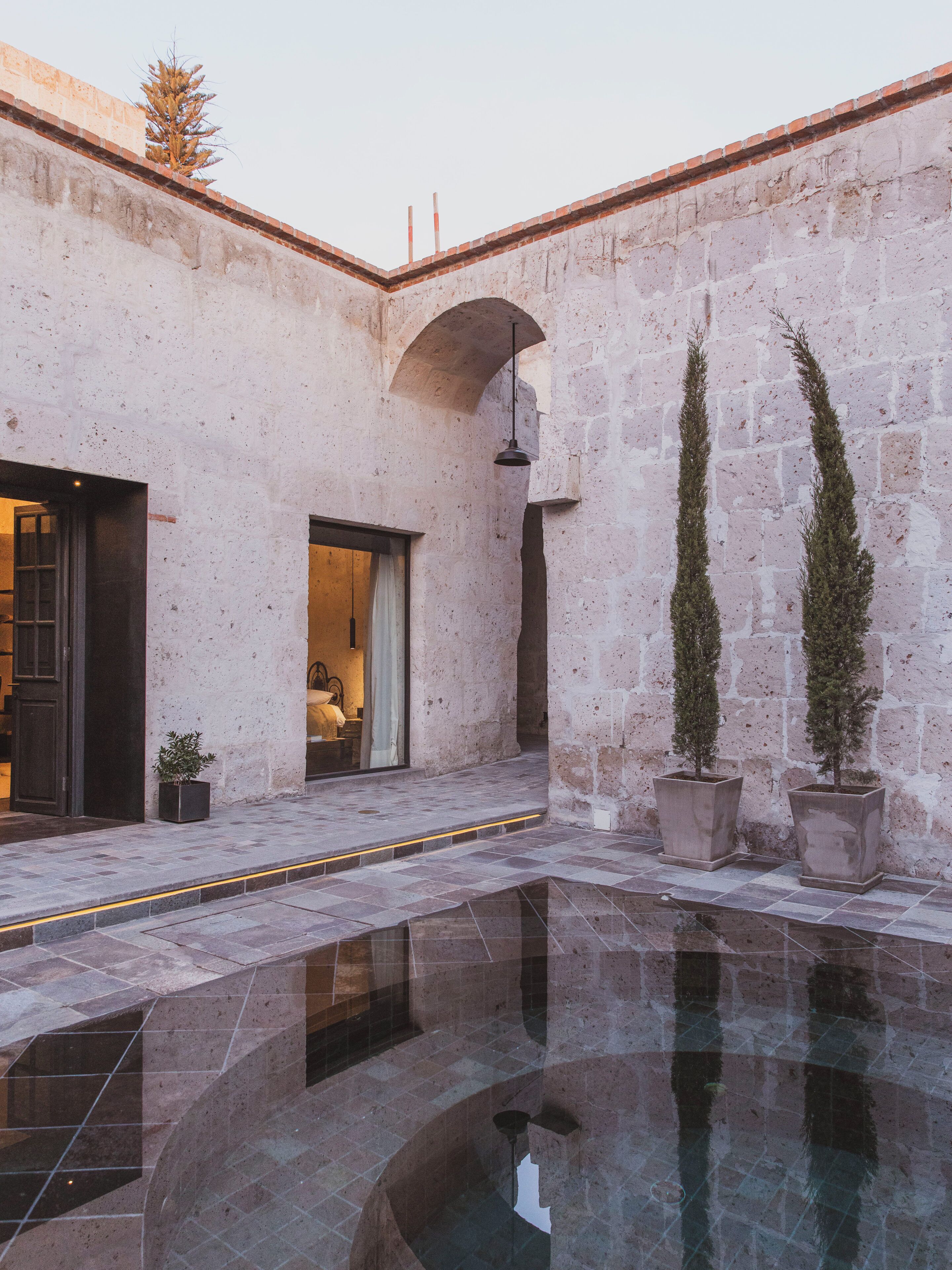 Un patio con piscina, muros de piedra y plantas en macetas.
