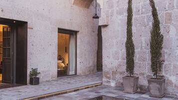 Un patio con piscina, muros de piedra y plantas en macetas.