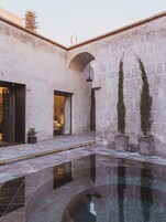 A courtyard with a pool, stone walls, and potted plants.