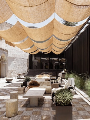 An outdoor seating area with tables and chairs, a stone floor, and a building in the background. - CIRQA by Andean (Arequipa)
