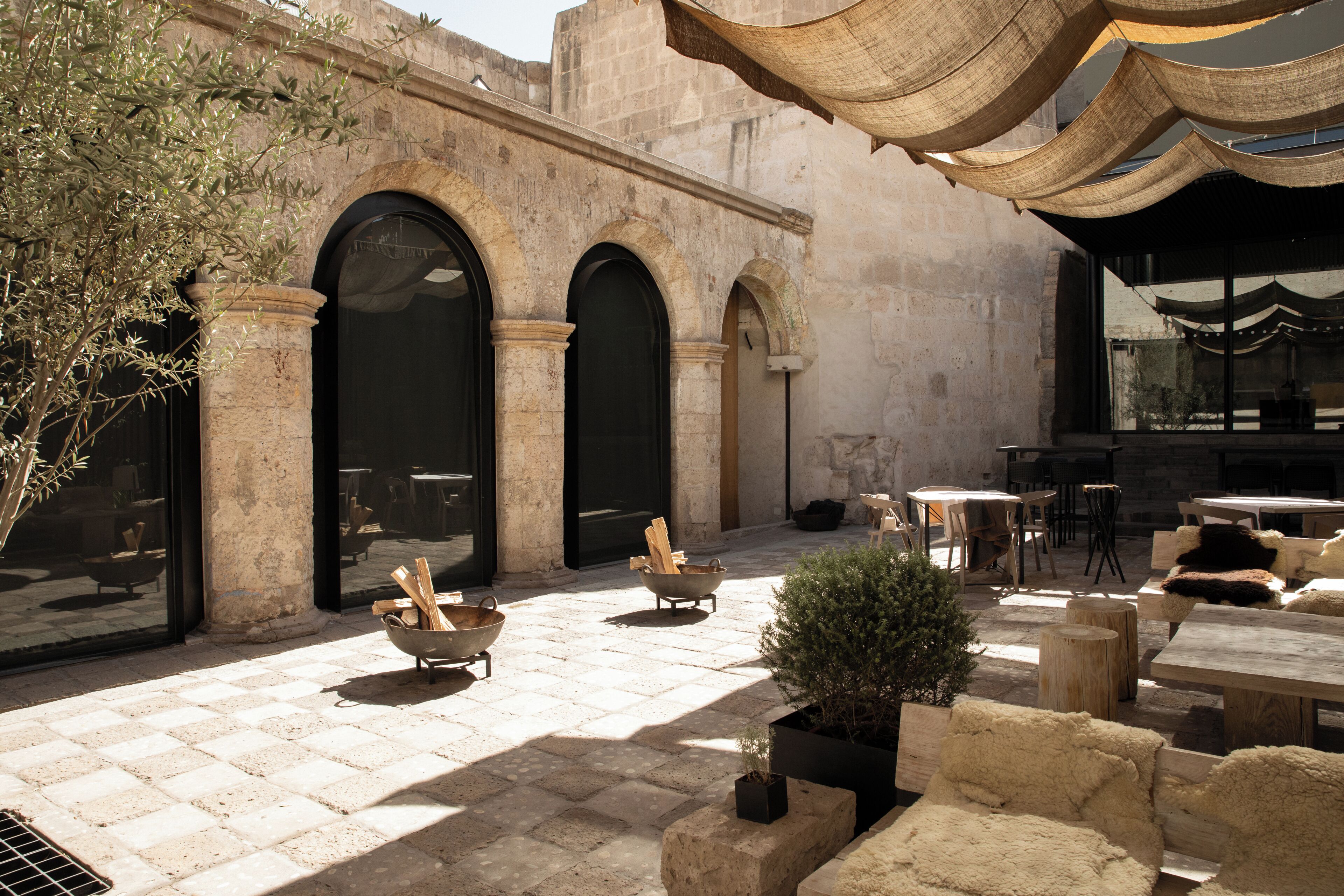 Un patio exterior con suelo de piedra, mobiliario de madera y una planta en maceta.