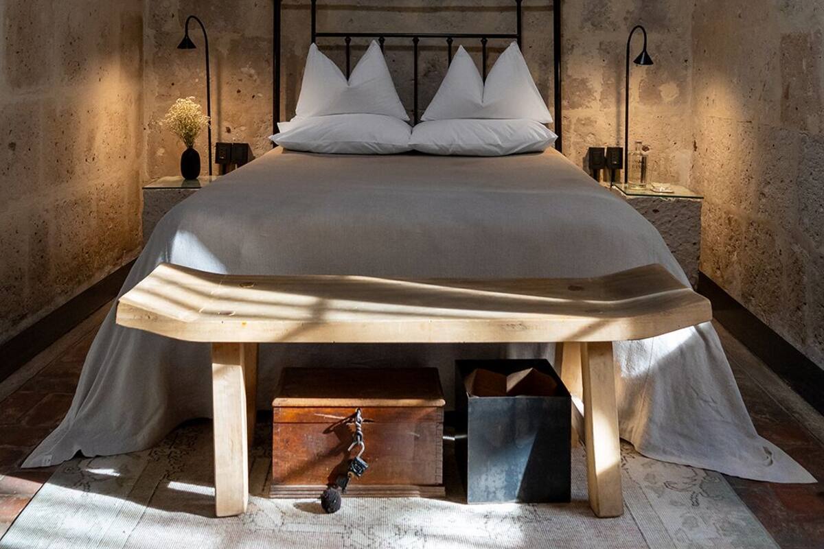 Ein Schlafzimmer mit Steinsturz, einem Bett mit weißen Leinen, zwei Nachttischlampen und einem Holznachttisch.
