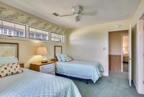 Un dormitorio con dos camas, ventilador de techo y ventana con vistas.