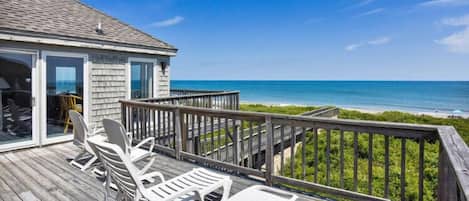 Una terraza de madera con muebles de exterior con vista a una playa.