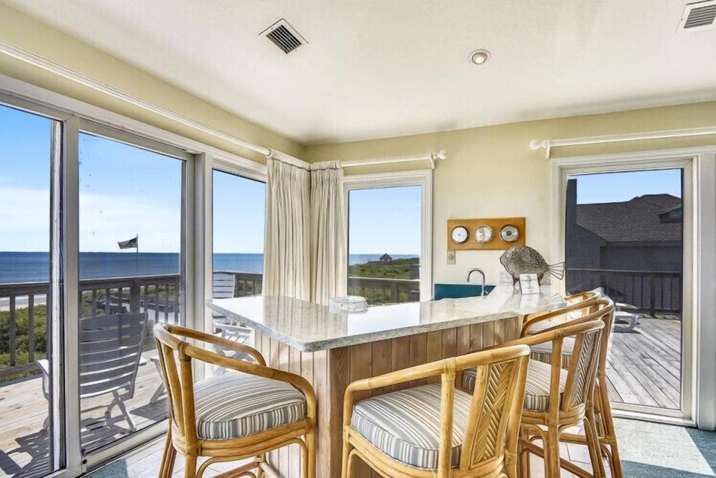 A balcony with a dining area featuring a bar and chairs, overlooking a scenic view.