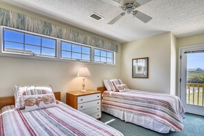 Two single beds with striped bedspreads and matching pillows, a nightstand with a lamp, and a framed picture adorn this cozy retreat.
