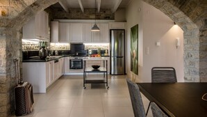 Eine Küche mit weißen Schränken, einem Edelstahlkühlschrank und einem Essbereich mit Tisch und Stühlen.