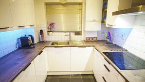 A kitchen with white cabinets, a stainless steel sink, a coffee maker, and a sign that says "IT'S ALL GOOD". - Superior Canary Wharf  O2 Arena 2Bed Apartment (Greater London)