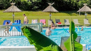 A swimming pool with lounge chairs and a slide, surrounded by a grassy area and a small building. - Le Val de la Marquise - Tente Lodge (Campagne)