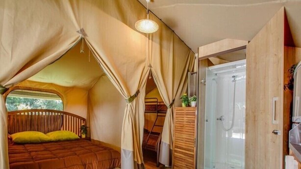 A tented room with a bed, a shower, and a wooden floor. - Le Val de la Marquise - Tente Lodge (Campagne)