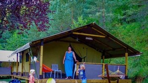 A rustic wooden cabin with a porch, a hammock, and a beach ball on the ground. - Le Val de la Marquise - Tente Lodge (Campagne)