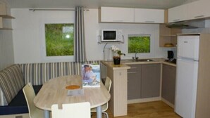 Uma cozinha compacta com área de refeições, incluindo um sofá listrado, uma mesa pequena e um micro-ondas.