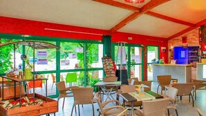 Un restaurante con barra, mesas al aire libre y una pantalla de televisión.