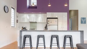 Una cocina moderna con armarios blancos, encimera de granito y tres taburetes negros.