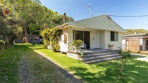 A single-story house with a front porch, a small garden, and a pathway leading to the entrance. - Pippis - a Classic Beach House (Seal Rocks)