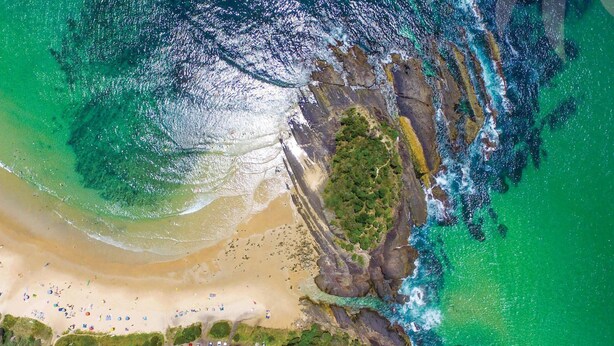 An aerial view of a beach with clear turquoise waters, a sandy shore, and rocky outcrops. - Pippis - a Classic Beach House (Seal Rocks)