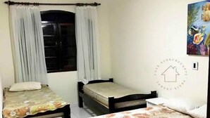 Una habitación con dos camas individuales, un ventilador de techo, una ventana con cortinas y un cuadro colgado en la pared.