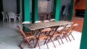 Un comedor con una mesa y sillas de madera, una pared verde y un horno de ladrillo.