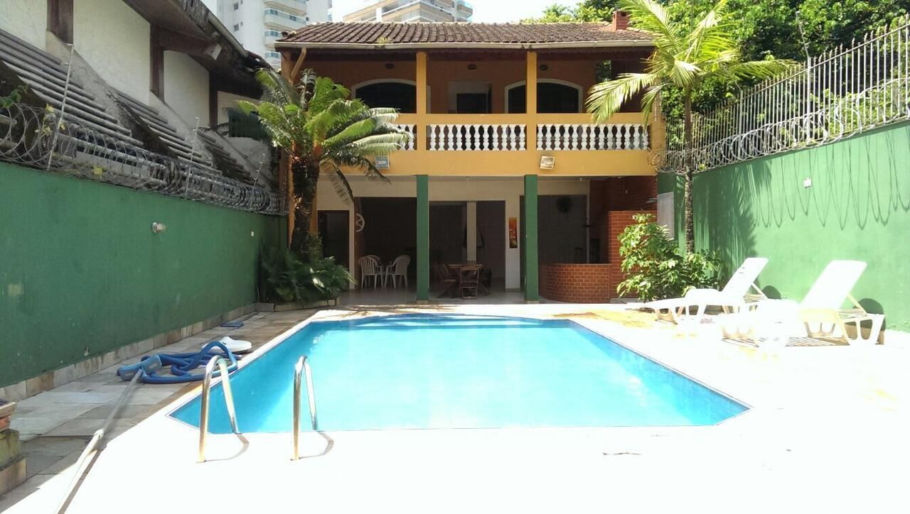 Piscina com espreguiçadeiras e um prédio de dois andares com varandas.