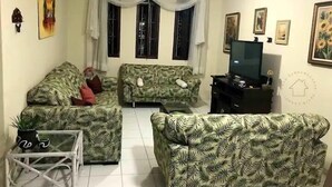Una sala de estar con dos sofás estampados, un televisor y una mesita.