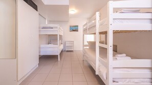 A corridor with bunk beds, a white wardrobe, and a small bedside table.