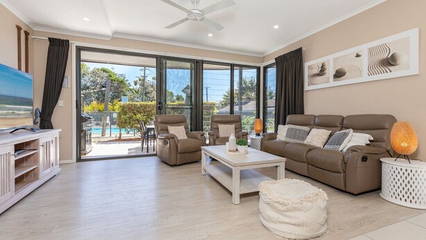 A spacious living room with a large sliding glass door leading to a pool area, a ceiling fan, and a view of the outdoors. - Boom 1 located just metres from Boomerang Beach one of the most beautiful beaches in Australia. (Boomerang Beach)