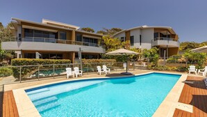 A modern hotel with a swimming pool, outdoor seating, and lush landscaping. - Boom 1 located just metres from Boomerang Beach one of the most beautiful beaches in Australia. (Boomerang Beach)