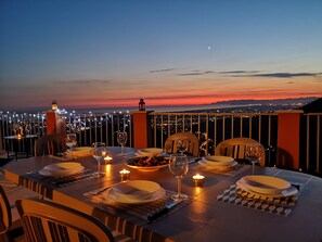 A table set for dining with candles and wine glasses, overlooking a cityscape at sunset. - La Rocca - casa con terrazza vista mare in borgo medievale (Camaiore)