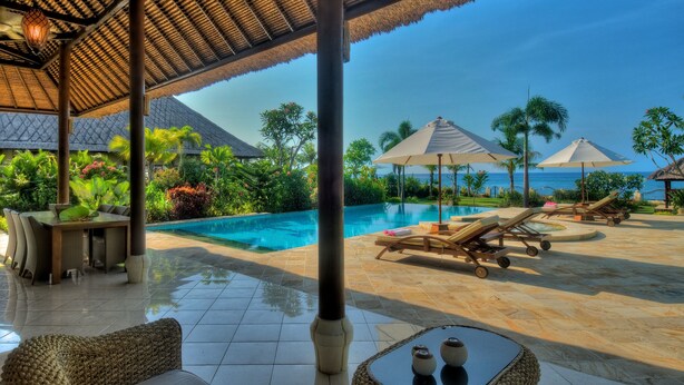 A poolside area with lounge chairs, umbrellas, and a view of the ocean.