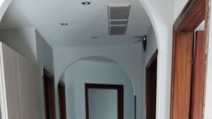 Ein Flur mit einem roten Sofa, Holzboden und einem Bett im Hintergrund.