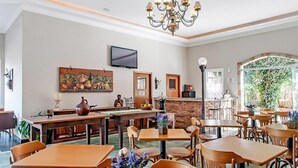Ein Restaurant mit Holztischen und -stühlen, einer Kristallleuchter, einem Fernseher und einer Ziegelwand.