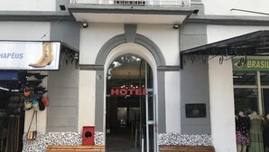 Ein Hotel Eingang mit einem Schild, zwei Bänken und einer Schaufensterfront mit Dummys.